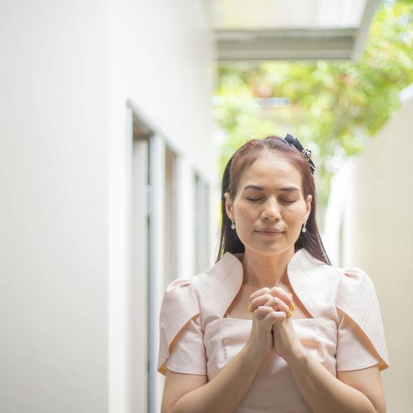 Person meditating outdoors with a serene natural background.